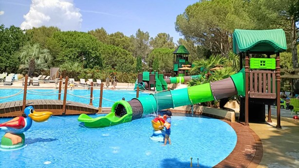 Een waterpark met een zwembad, glijbanen en speelconstructies.