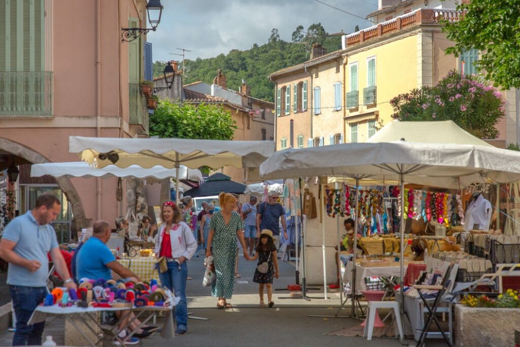 Un marché animé en plein air, avec de nombreux étals et beaucoup de monde qui se promène.