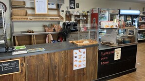 Een café toonbank met een menubord, een koffieapparaat en een presentatie van snacks en dranken.