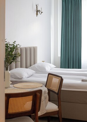 A neatly arranged hotel room with a bed, a chair, a small table, and a wall-mounted light fixture. - RentPlanet - Apartament Chmielna (Warsaw)