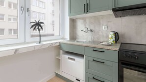 A kitchen with a window, a sink, a stove, and cabinets. - Cozy Studio in the Center | Workspace (Gdynia)