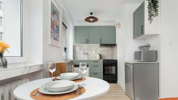 A compact kitchen with a dining area, a refrigerator, and a microwave. - Cozy Studio in the Center | Workspace (Gdynia)