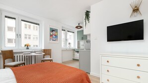 A modern hotel room with a bed, a desk, and a kitchenette. - Cozy Studio in the Center | Workspace (Gdynia)