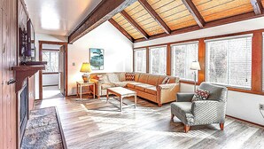 A spacious living room with a high ceiling, wooden beams, a sofa, armchairs, a coffee table, and large windows with blinds. - Family-Friendly Shenandoah Townhome – Near Lake Laura & Hiking Trails (Basye)