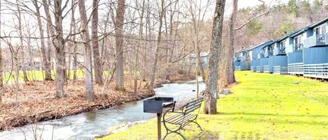A bench by a river with a building in the background.