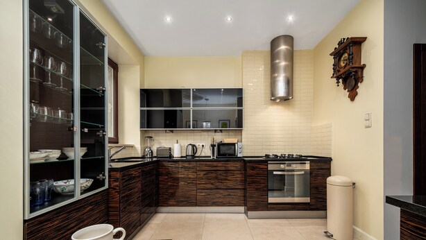 Una cocina moderna con armarios de madera oscura, una campana extractora de acero inoxidable y un microondas.