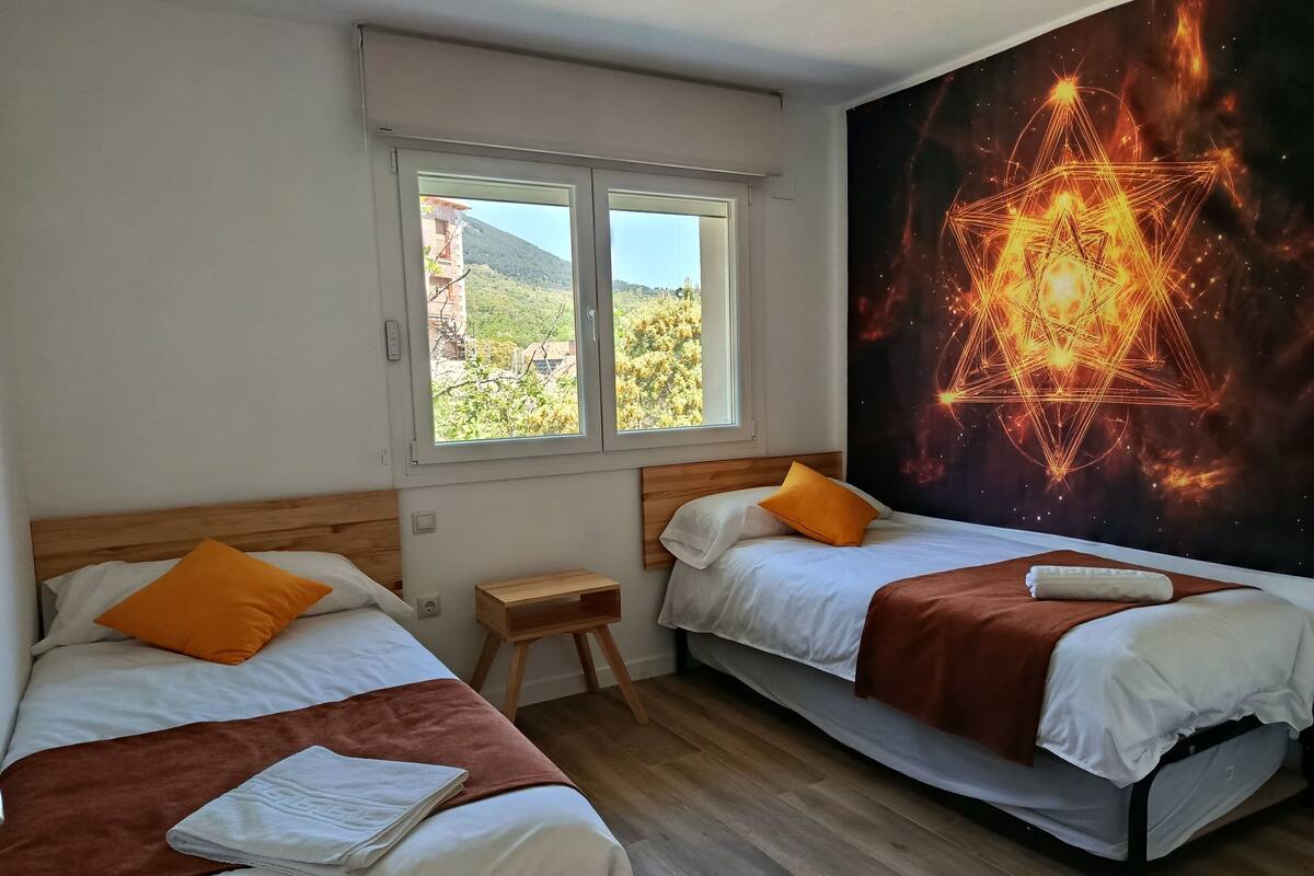A room with two beds, a window, and a wall mural.