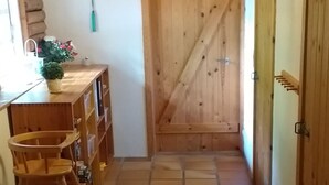 A narrow hallway with wooden flooring, a wooden door, and a small wooden stool. - "Kerrin" by Interhome (Aars)