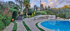 Ein Garten mit Swimmingpool, einer Steintreppe und einem Himmelbett.