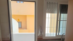 Una cocina moderna con un amplio ventanal, una puerta corredera a un balcón y suelo de madera.