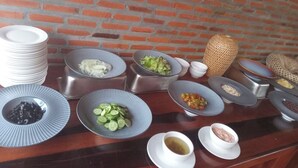 Une table de buffet garnie de divers plats et de bols remplis de nourriture, placée devant un mur de briques.