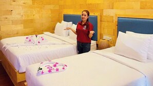 Une chambre d’hôtel avec deux lits, des murs en bois et un ventilateur de plafond.
