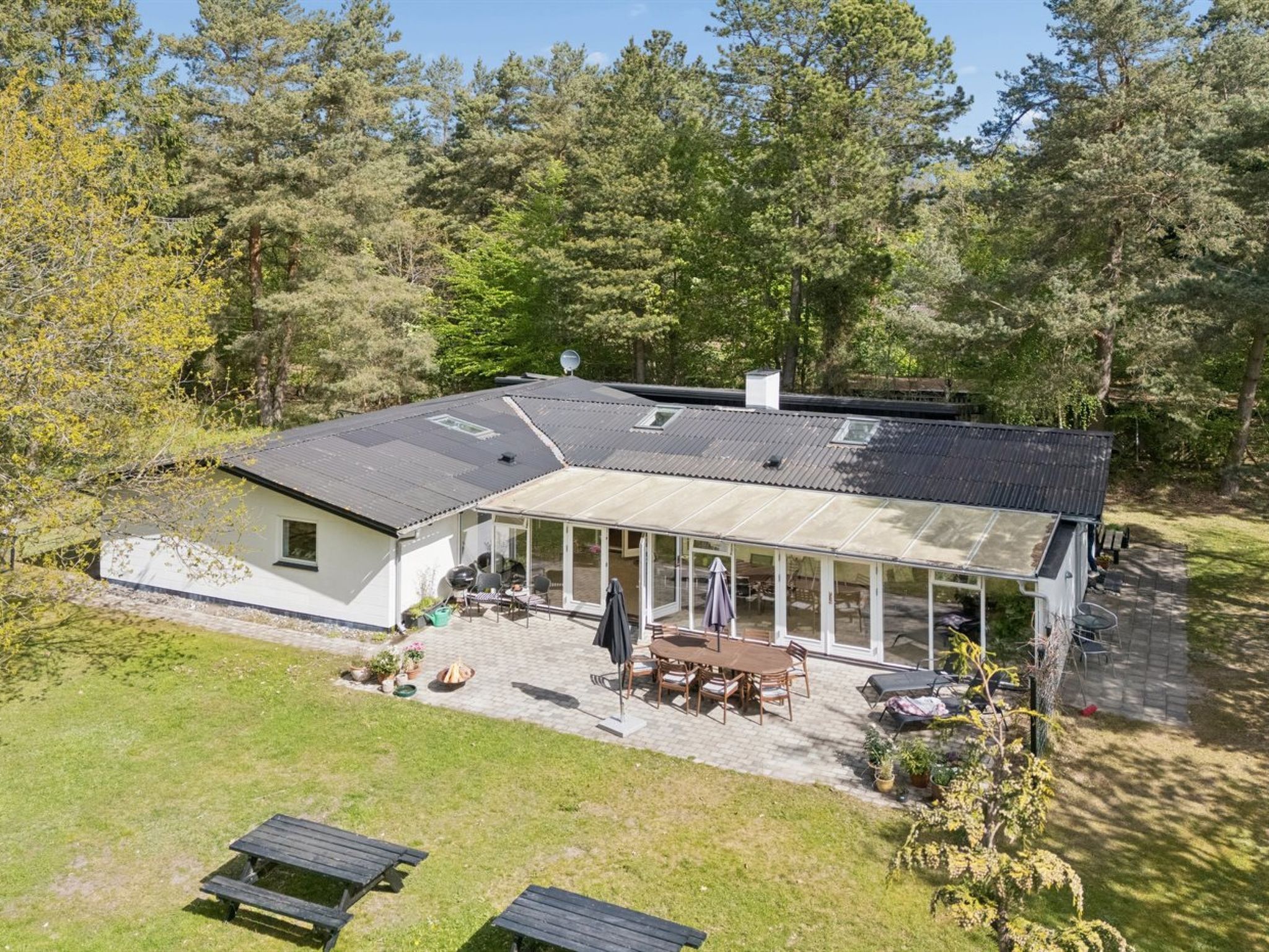 A modern house with a large patio, a covered outdoor dining area, and a satellite dish.