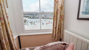 A room with a view of a harbor, a chair, and a radiator. - Pelican Cottage (St Ives)