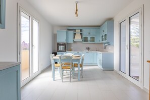 Una cucina moderna con mobili azzurri, un tavolo da pranzo con sedie e un'ampia finestra che lascia entrare la luce naturale.