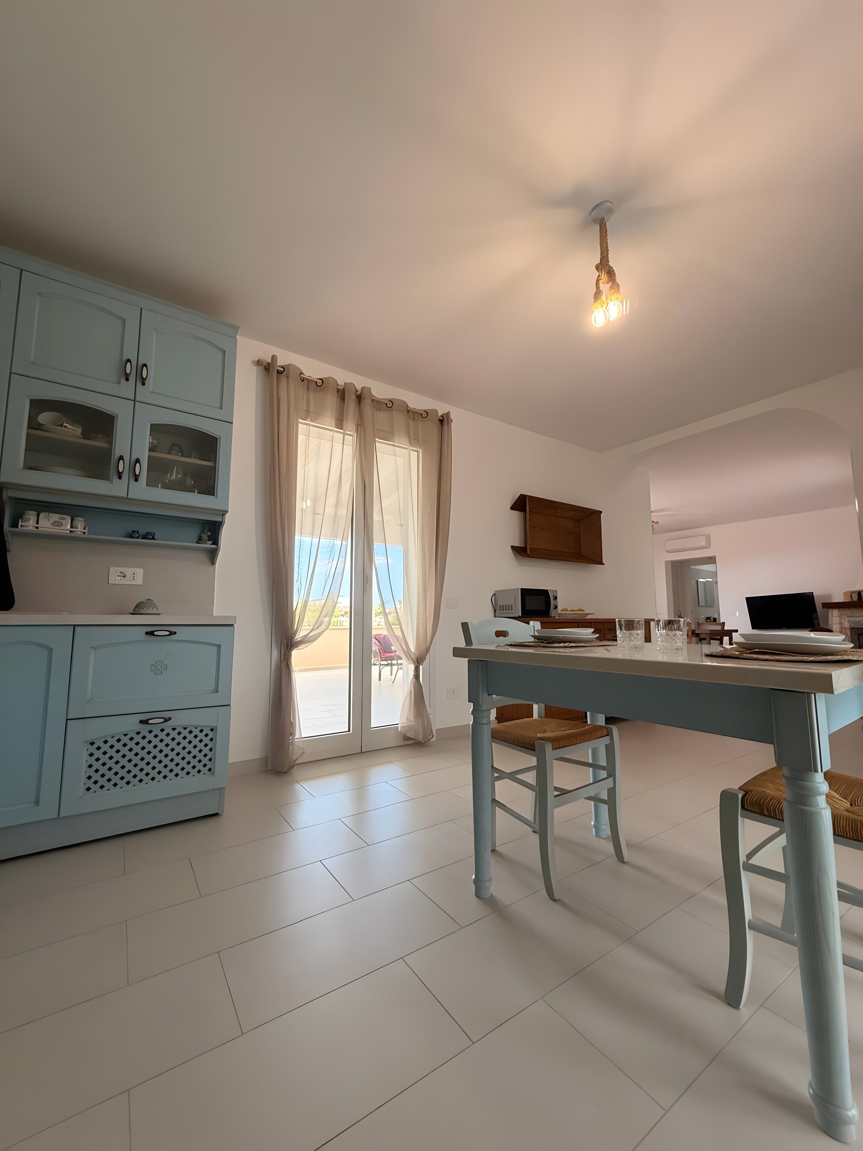Une cuisine équipée d’une table à manger, de chaises, d’un four à micro-ondes et d’un ordinateur portable.