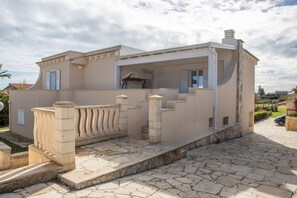 Une maison à deux étages avec une façade en pierre, un balcon et une allée pav ée.