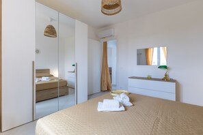 Une chambre à coucher moderne avec un grand lit, un miroir, une table de chevet avec une lampe et une armoire.