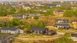 Un quartier résidentiel composé de maisons, dont certaines sont dotées de garages attenants, entouré de verdure et offrant une vue sur la mer.