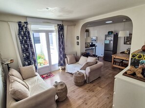 Ein Wohnzimmer mit einer Sofagarnitur, einem Esstisch und einem durch einen Bogen sichtbaren Küchenbereich.