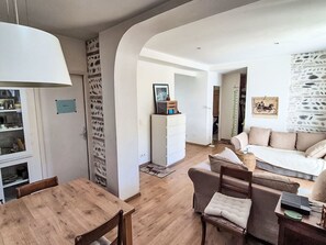 A modern living room with a wooden dining table, a sofa, and a white cabinet. - Gästezimmer "Toulousaine arborée". by Interhome (Toulouse)