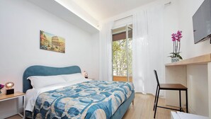 A bedroom with a bed, a desk, a chair, a TV, and a painting of a building. - Foro Italico Guesthouse (Rome)