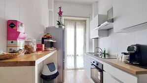 A modern kitchen with white cabinets, a stainless steel sink, and a coffee machine. - Foro Italico Guesthouse (Rome)