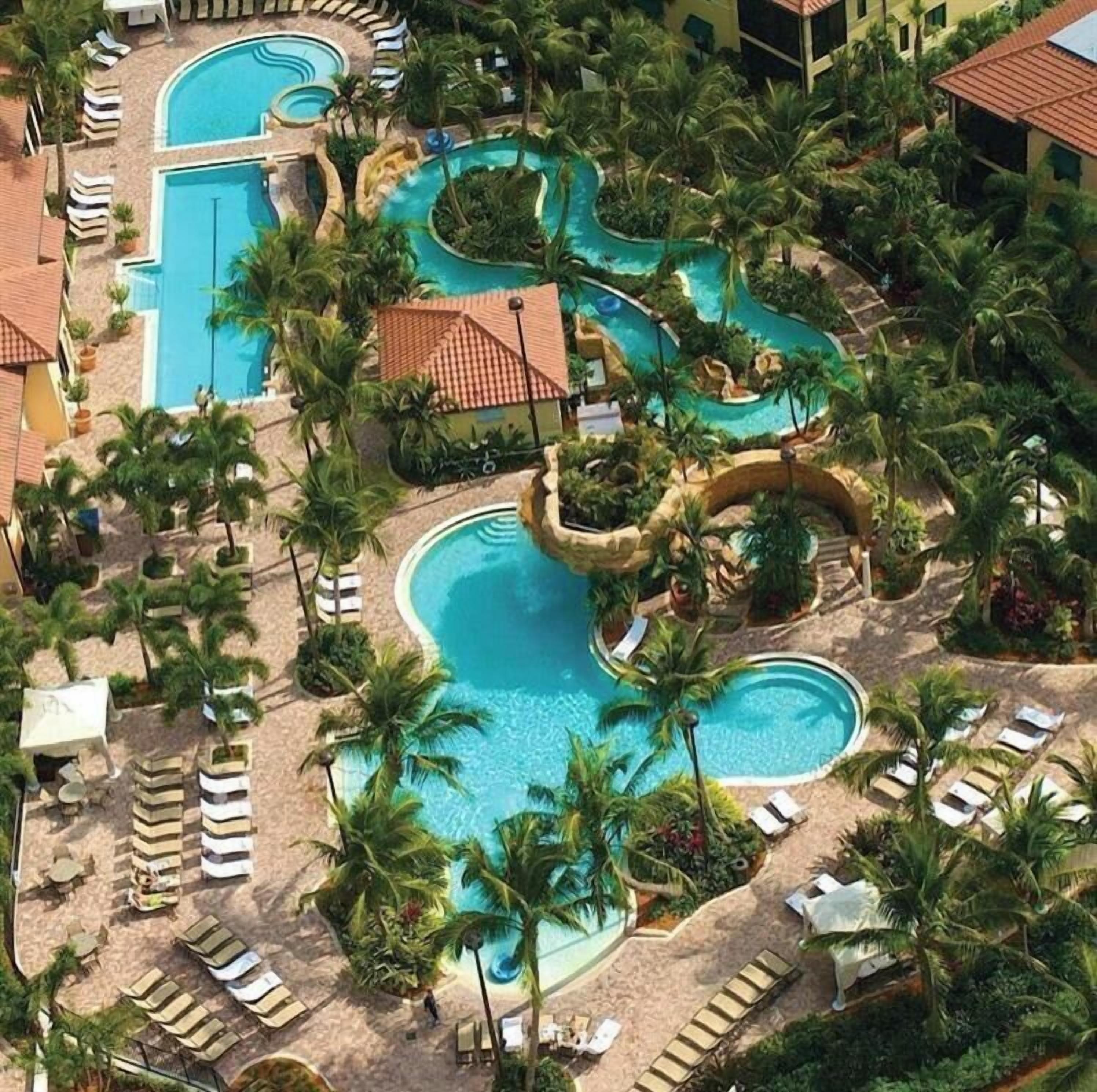 A resort with multiple swimming pools, palm trees, and lounge areas.