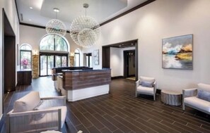 Eine moderne Lobby mit einer Rezeption, einer Sitzecke und großen Fenstern.