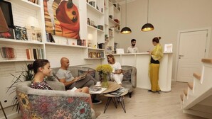 A modern interior with a reception desk, seating area, and bookshelves. - Citrus Boutique Hotel (Baku)