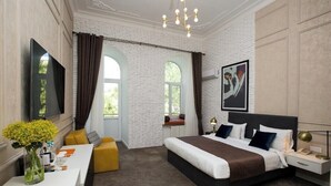 A modern hotel room with a large bed, a desk, a sofa, and a TV. - Citrus Boutique Hotel (Baku)