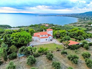A coastal property with a central building surrounded by greenery, a body of water, and a distant town. - Charly Point Villa-Apartment, Doppelzimmer by Interhome (Evangelismos)