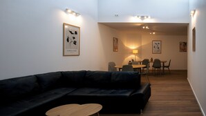 A modern living room with a black leather sofa, a wooden coffee table, and a dining area with a table and chairs. - Moderne City Zimmer mit eigenem Bad (Bamberg)