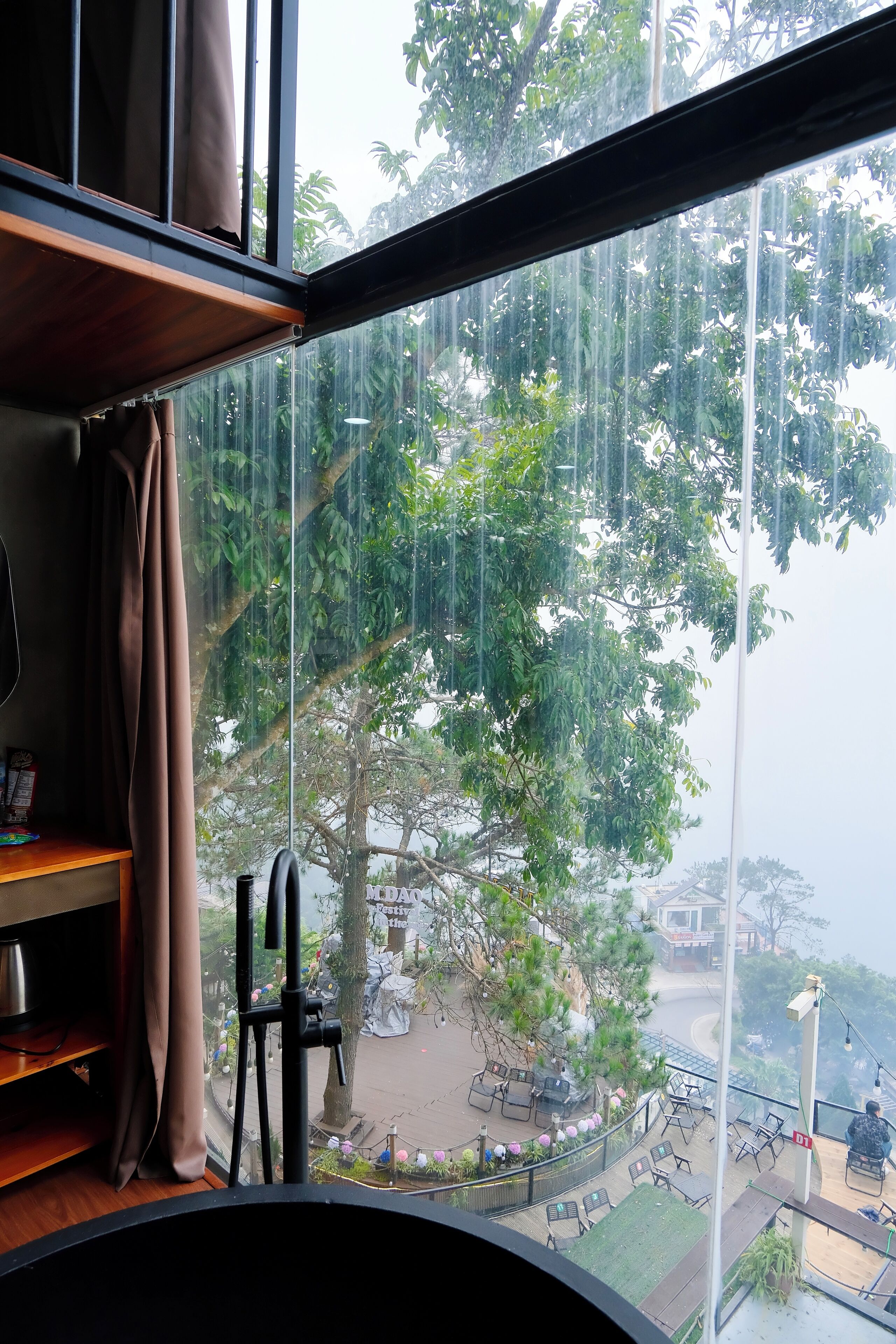 A room with a large window overlooking a street with trees and a view of a park.