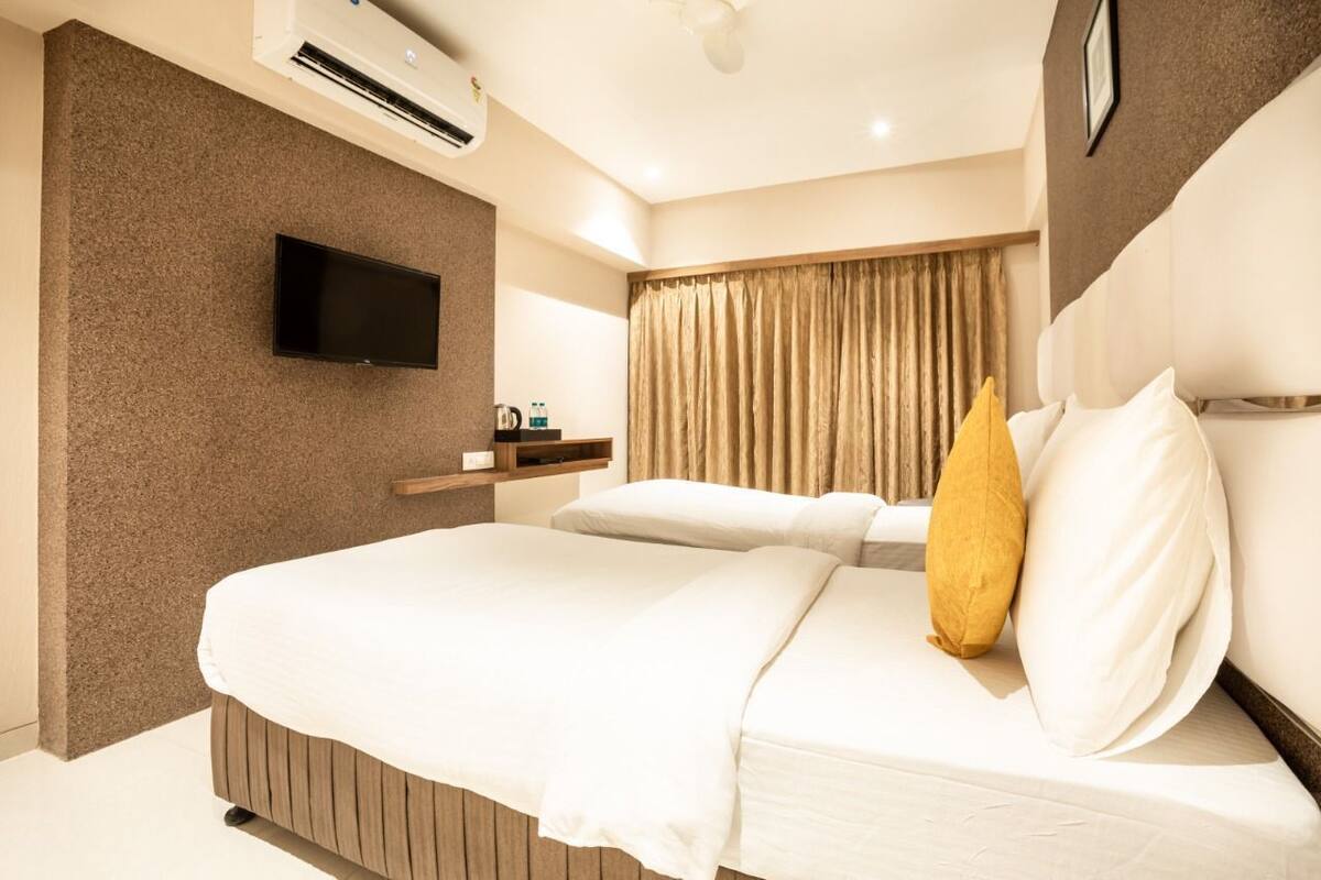 Una habitación de hotel moderna con una cama grande, un televisor de pantalla plana montado en la pared y un aire acondicionado integrado.