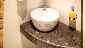 Un baño con lavamanos blanco, espejo y toallero.