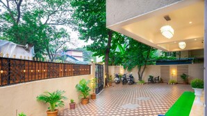 Un patio con suelo de ajedrez, plantas en macetas, una entrada con reja y una zona de estar con sillas.