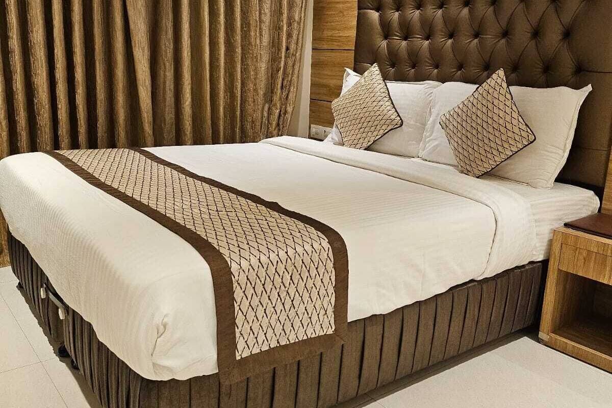 Una cama grande con cabecera capitonada, una mesita de noche de madera y un corredor de cama estampado.