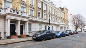 A row of terraced houses with a black car parked on the street. - Traditional 1 Bed Apartment, Pimlico (London)
