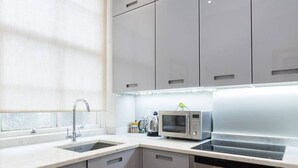 A modern kitchen with a sink, a microwave, and a stove. - Traditional 1 Bed Apartment, Pimlico (London)