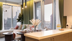 Una sala de estar moderna con sofá, mesa de comedor y vistas a la ciudad.