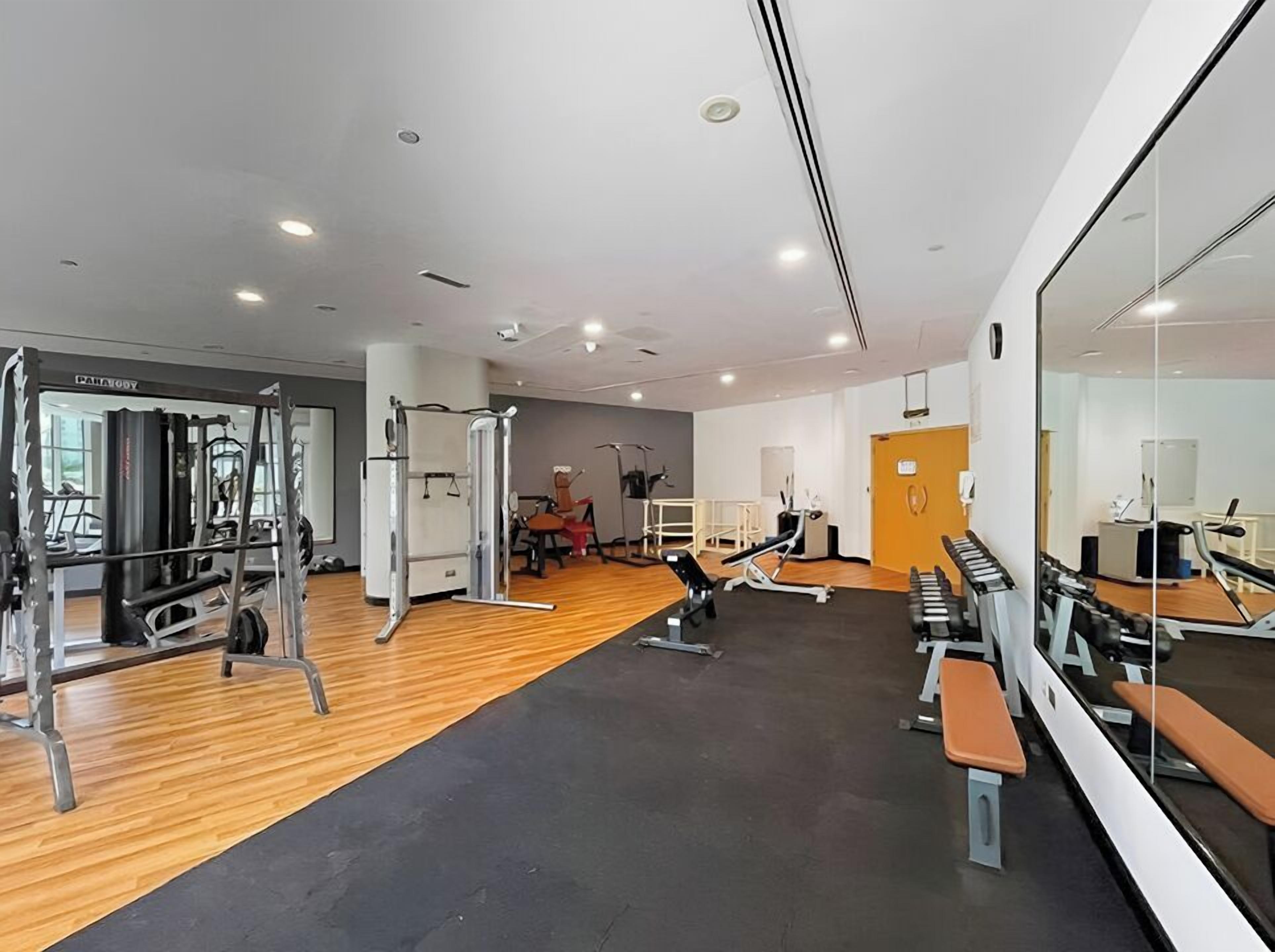 Una palestra con diverse attrezzature per esercizi, pavimento in legno e parete con specchi.