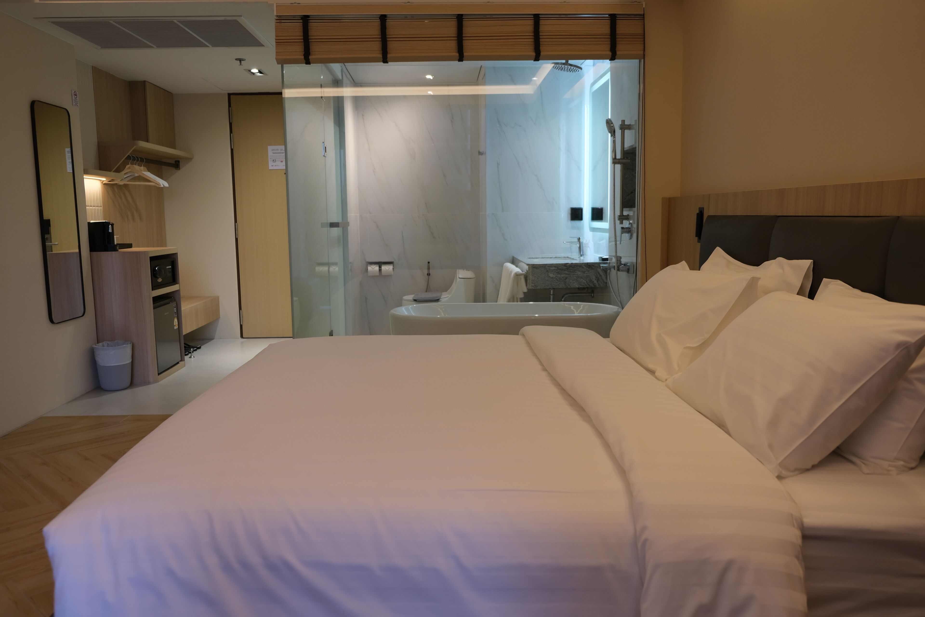 A modern hotel room with a large bed, a bathroom with a bathtub, and a walk-in closet.