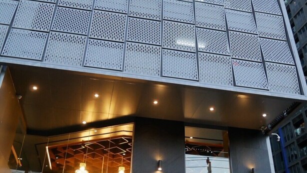 A modern building with a grid-patterned facade, large glass windows, and a well-lit entrance area.