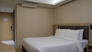 A hotel room with a bed, a wooden headboard, a bedside table, and a door.