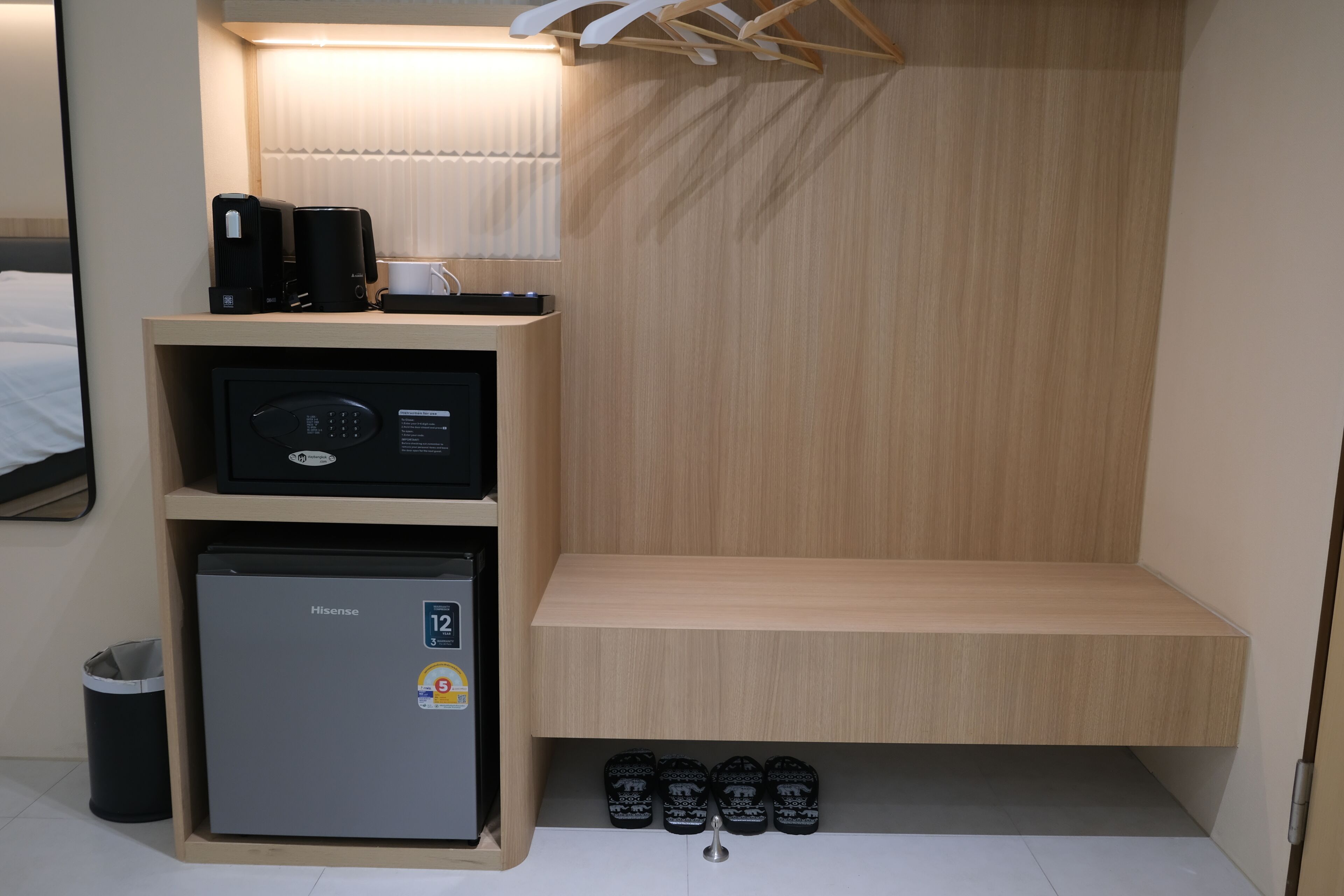 Ein kompaktes Hotelzimmer mit Minibar, kleinem Kühlschrank, Sitzecke und Schuhablage.