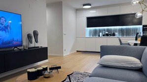 Een moderne woonkamer met een flatscreen televisie, een salontafel en een grijze bank.