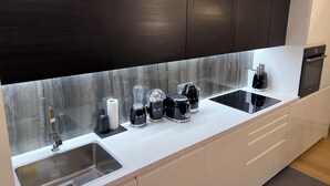 Een moderne keuken met donkere kastjes, een wit aanrechtblad en diverse apparaten, waaronder een koffiezetapparaat en een broodrooster.