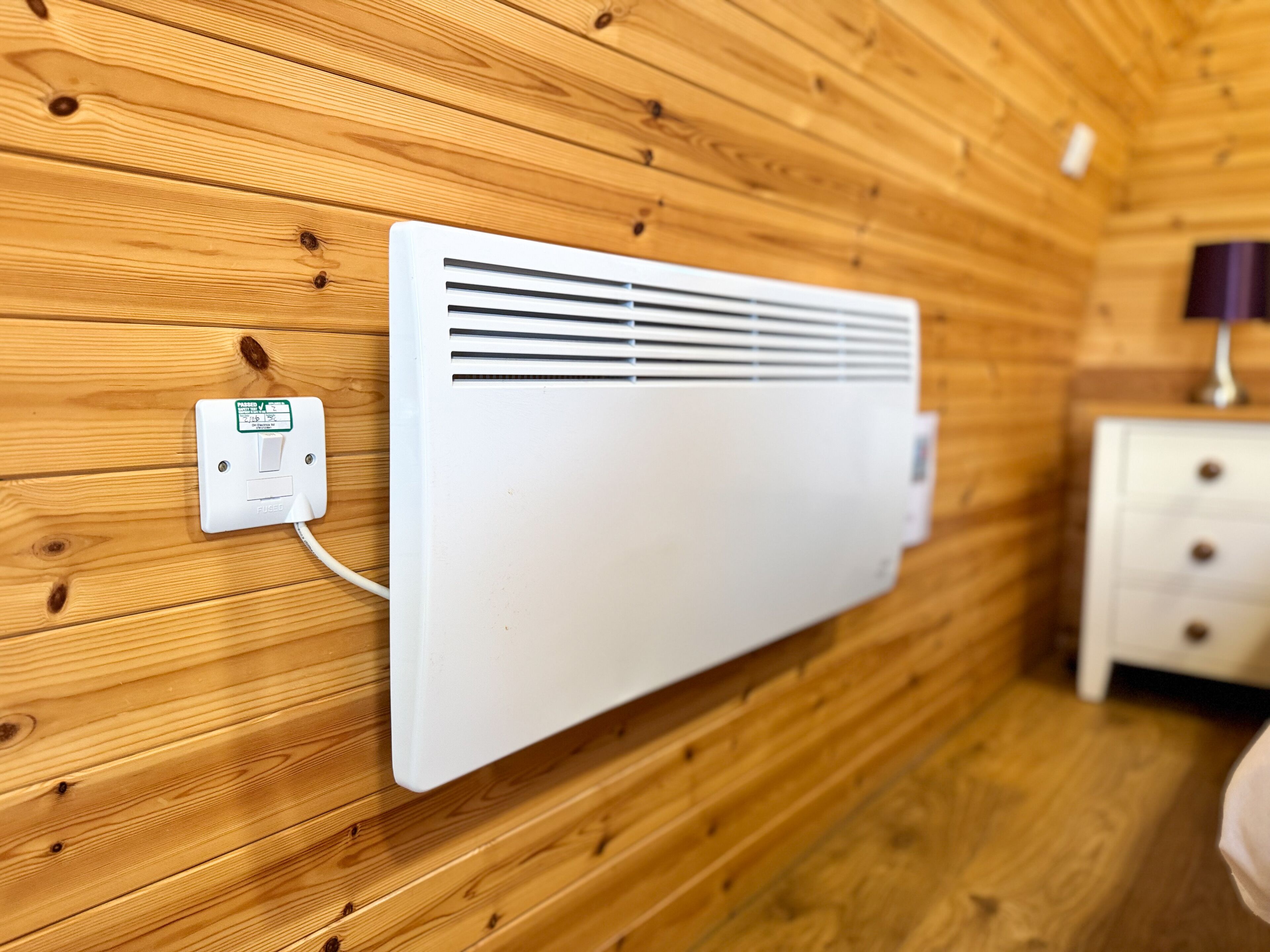 Un climatiseur blanc fixé au mur, dans une pièce dont les murs sont recouverts de lambris en bois.