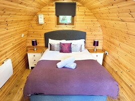 Um quarto acolhedor com painéis de madeira, uma cama, duas mesas de cabeceira e uma janela com vista.